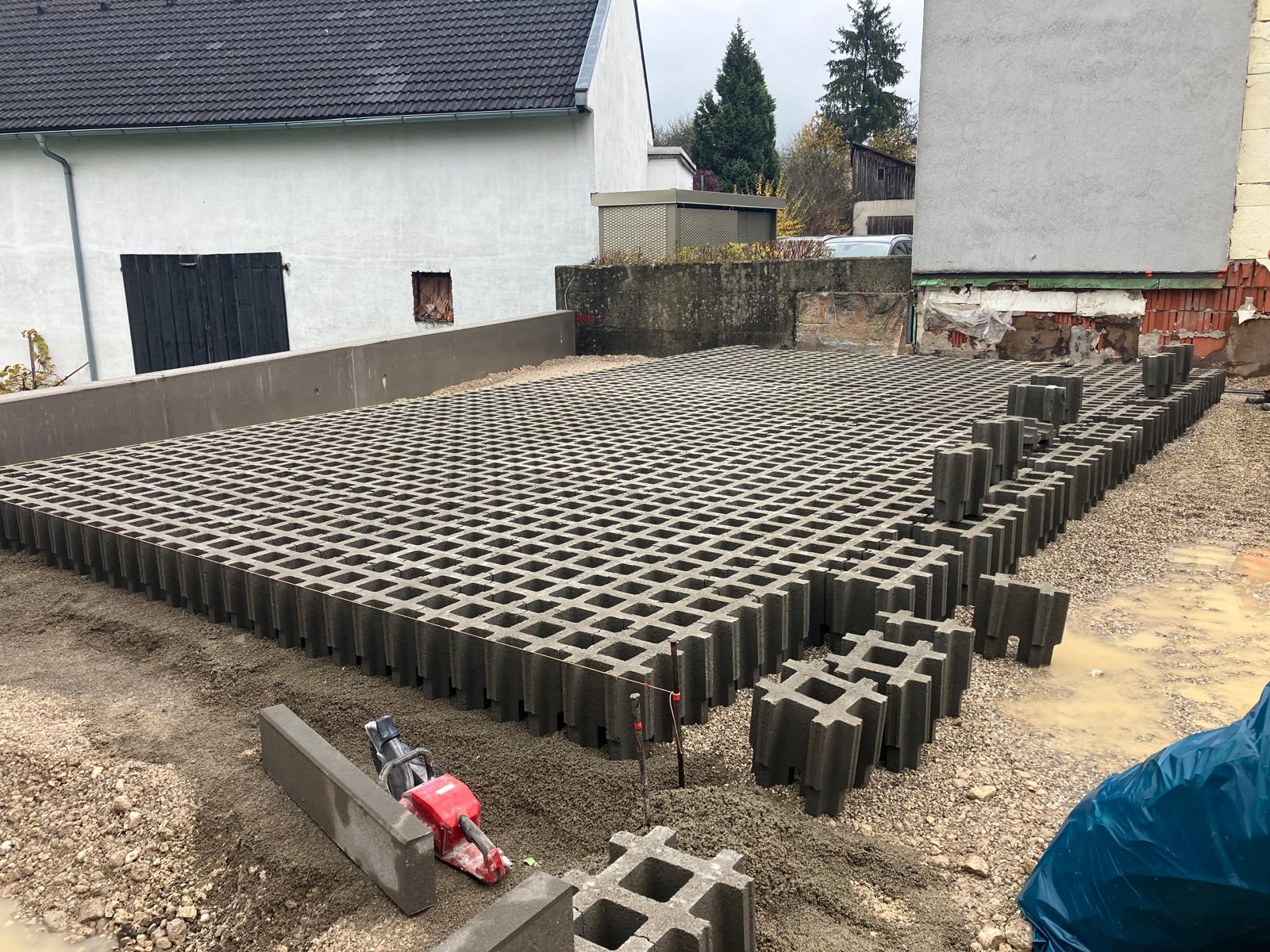 Staveniště u domu, betonové schody a dlažba, vedle dodávky s logem Sanserv a Strabag.